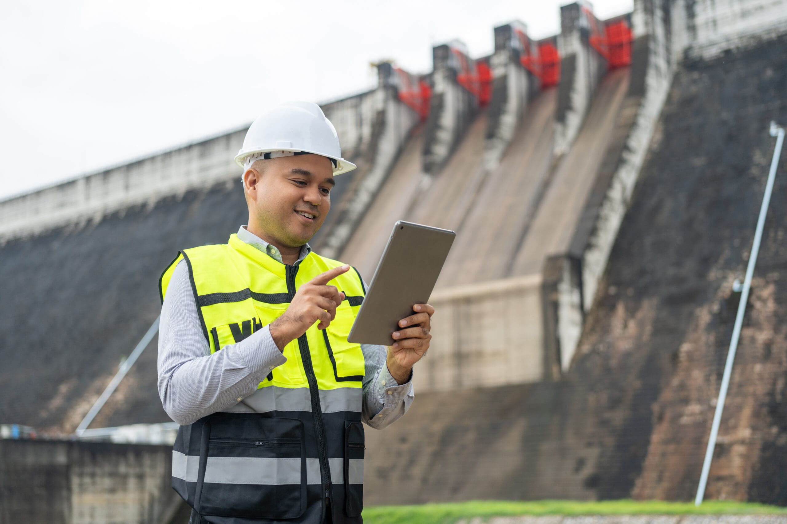 Professional maintenance engineer with safety helmet using EpochField at a hydroelectric power plant and irrigation.