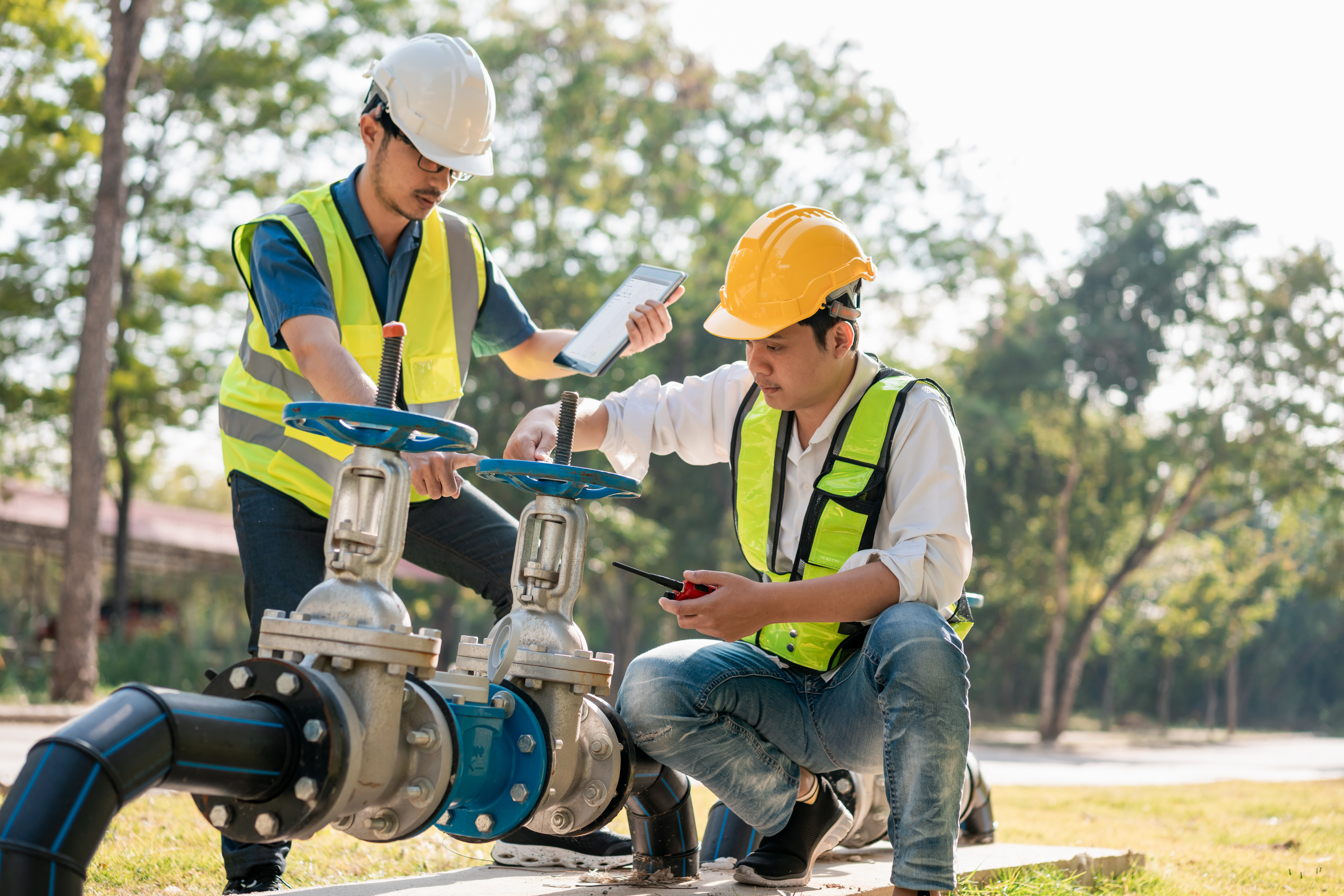 workers inspecting valves outdoors with tablet